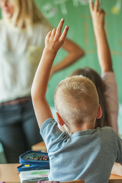 Children raising their hand in a classroom